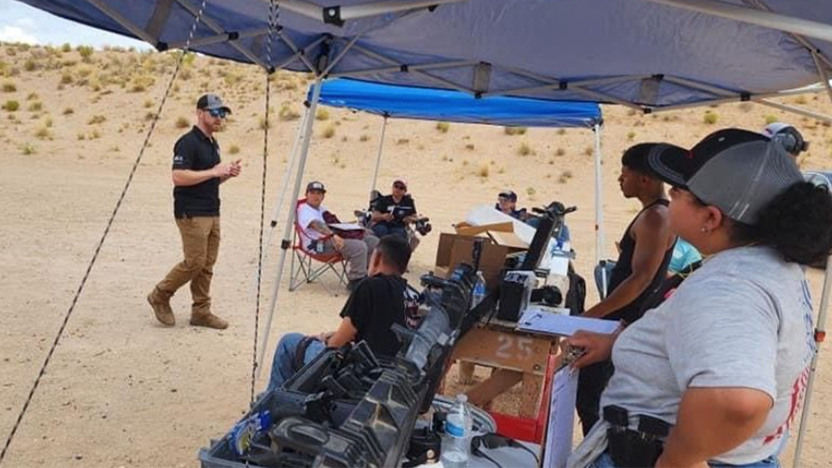 instructor at gun class addresses students at outdoor range