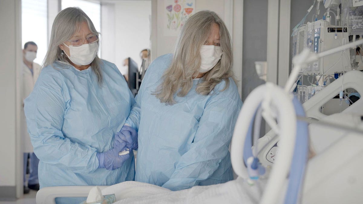 women stand next to patient in hospital