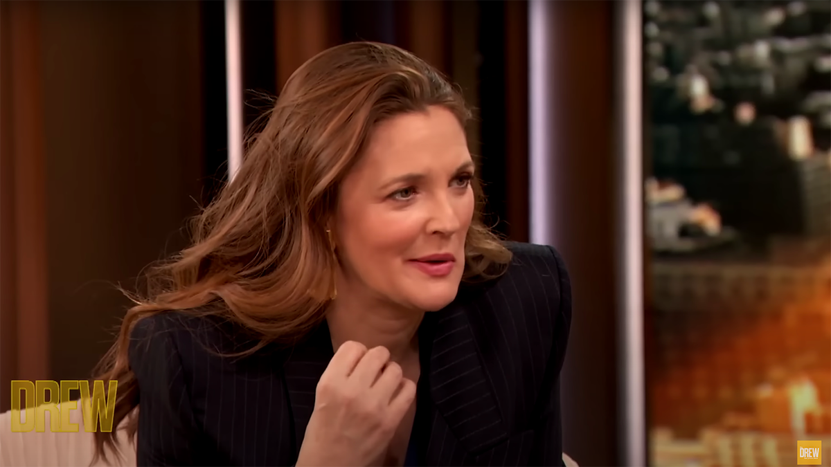 Drew Barrymore in a black blazer leaning over in an interview on "The Drew Barrymore Show"