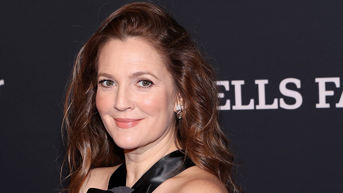 Drew Barrymore soft smiles on the carpet in a halter black gown at the Mark Twain Prize