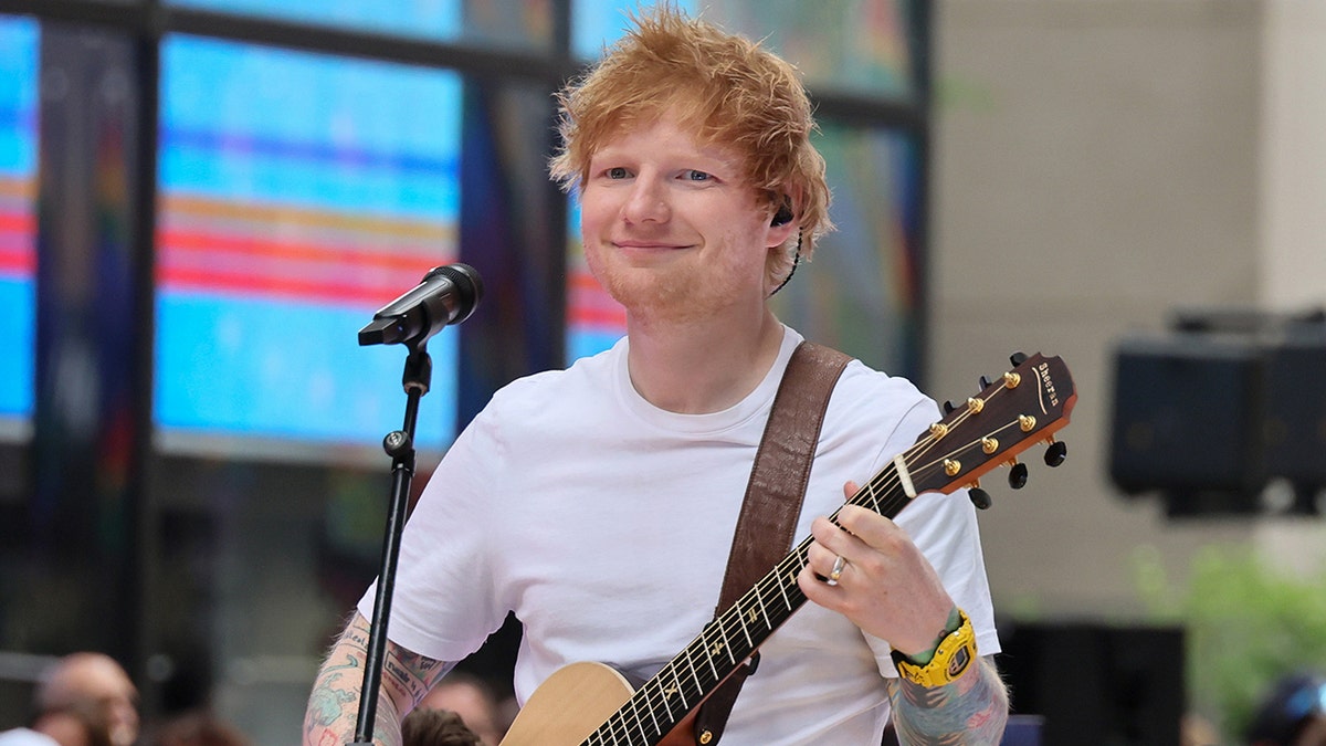 Ed Sheeran holds guitar while performing concert
