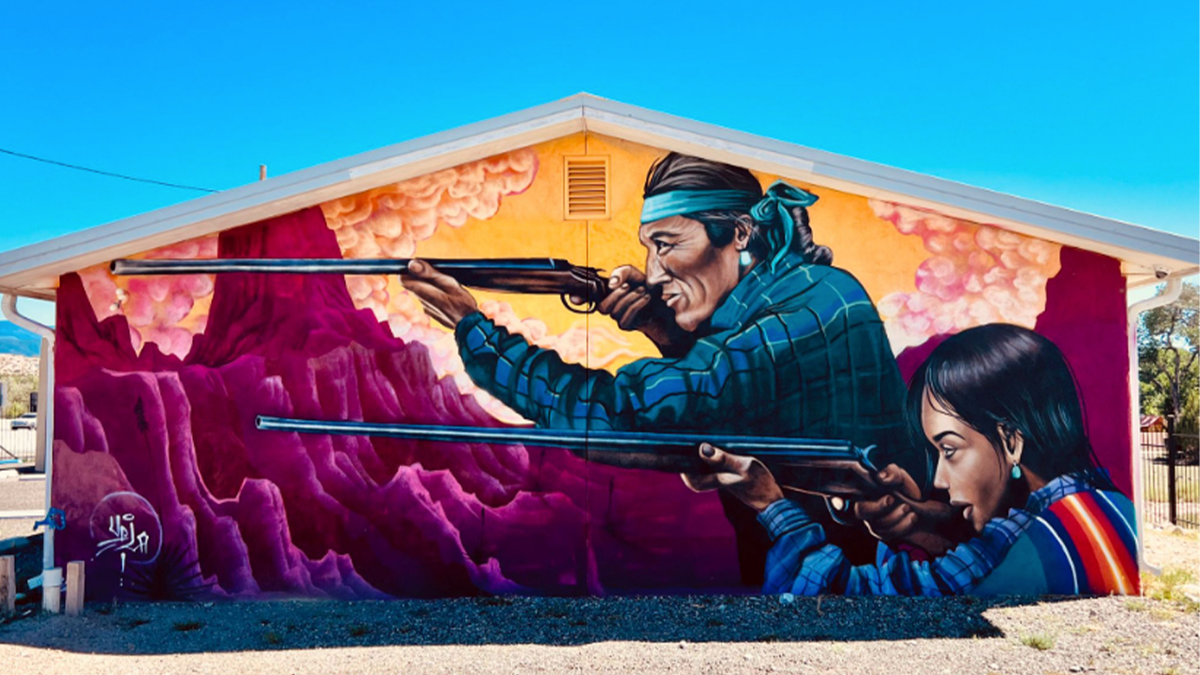 Mural on building showing Indians with rifles