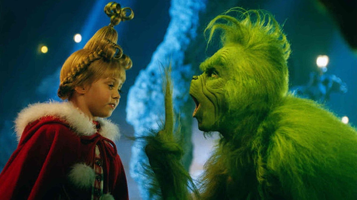 Taylor Momsen as Cindy Lou Who looks at the Grinch played by Jim Carrey who is putting up one finger to her