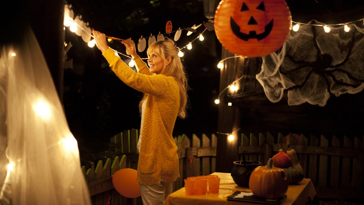 Woman decorating yard with Halloween decor.