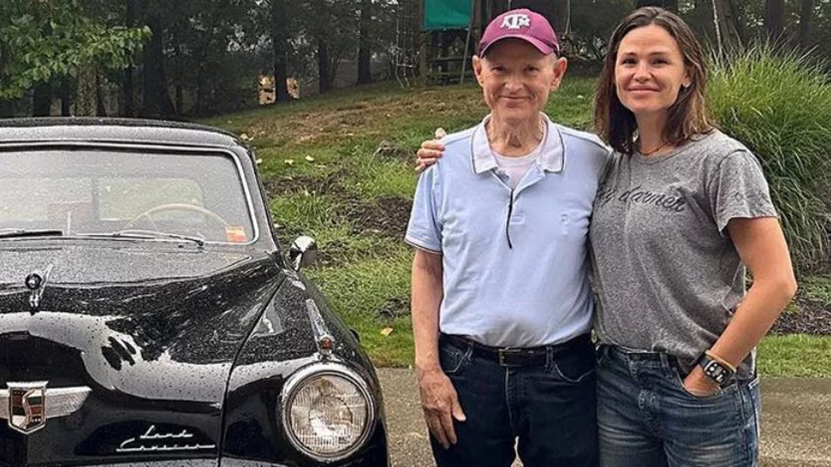 Jennifer garner standing with her dad in front of a 1948 Studebaker