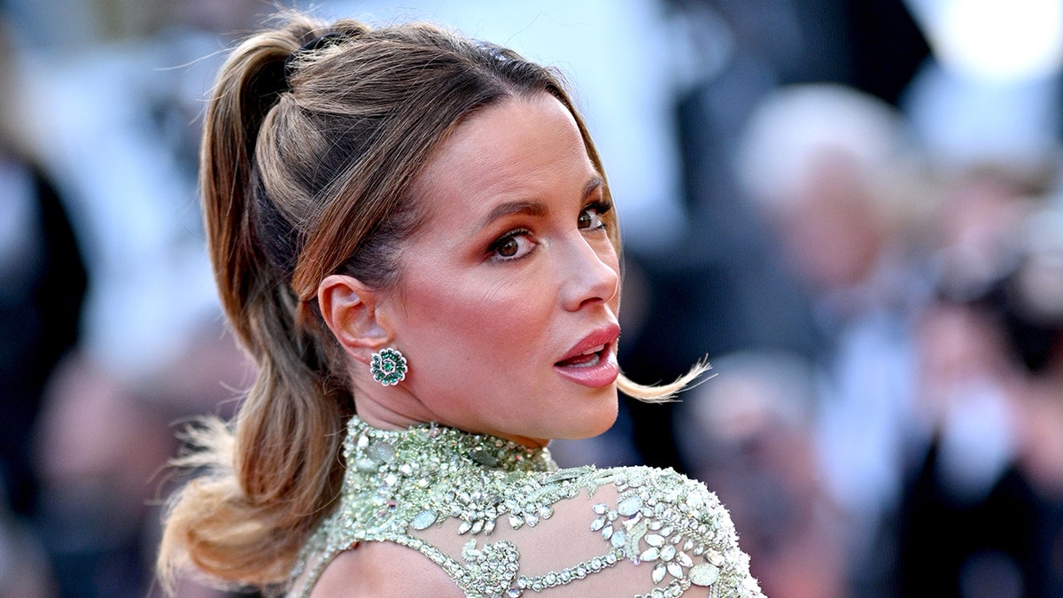 Kate Beckinsale looks over her shoulder in a soft light green lace dress in Cannes