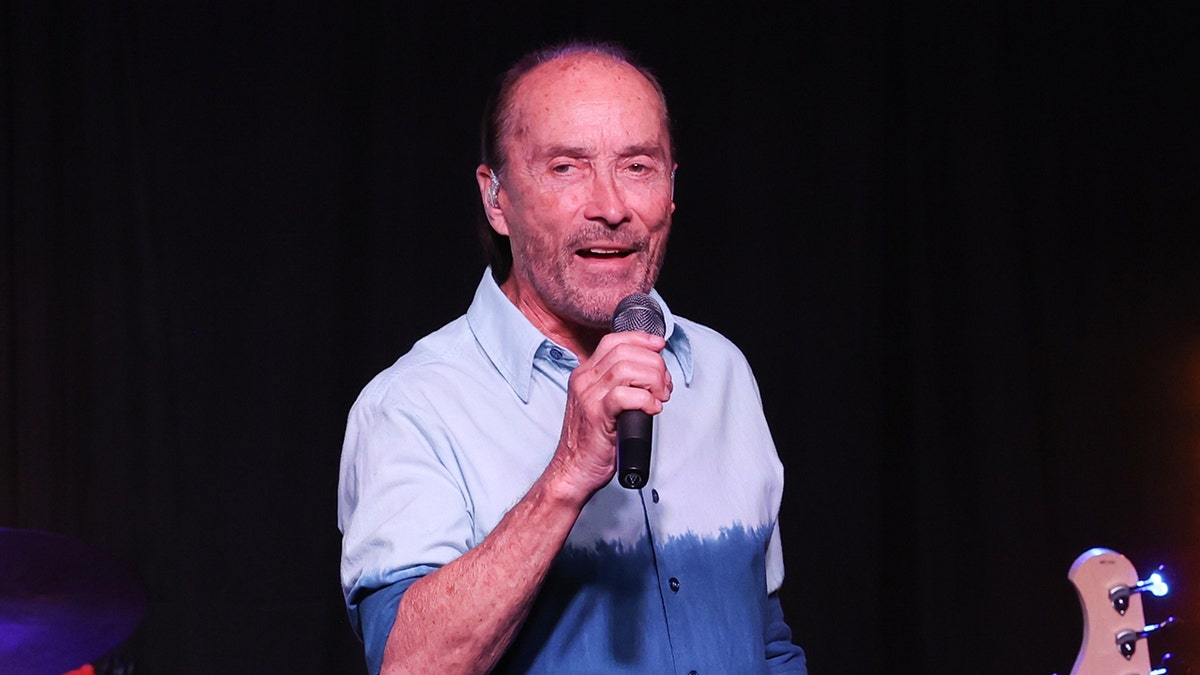 Lee Greenwood holds a microphone on stage