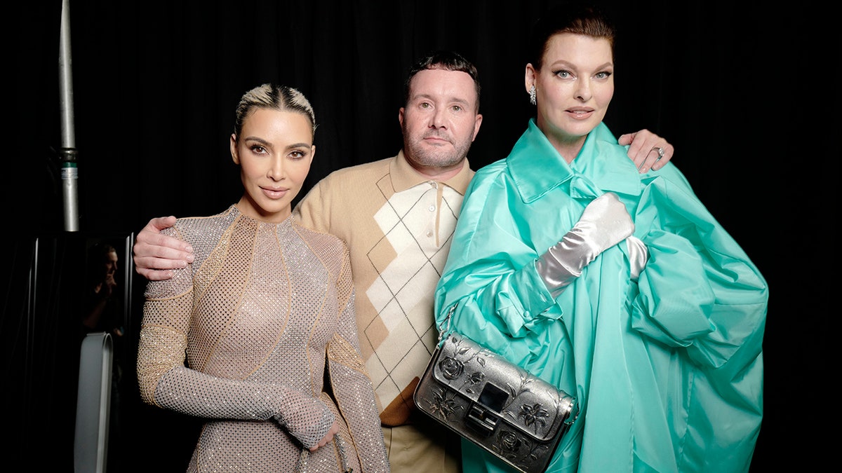Kim Kardashian in a jumpsuit poses next to Kim Jones in a sweat who poses next to Linda Evangelista in a turquoise coat at the Fendi Spring 2023 show