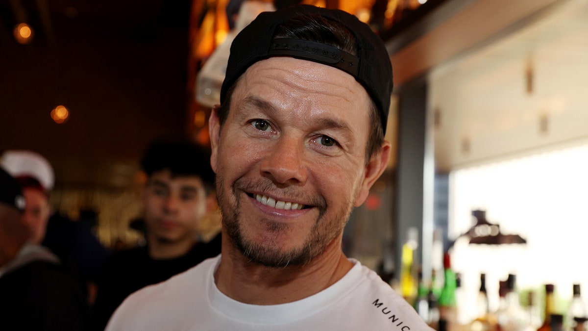 Mark Wahlberg in a white t-shirt and black backwards hat