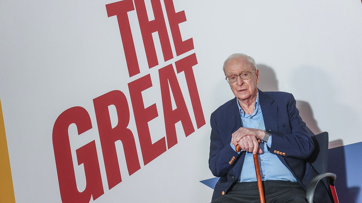 Michael Caine sitting in front of a 