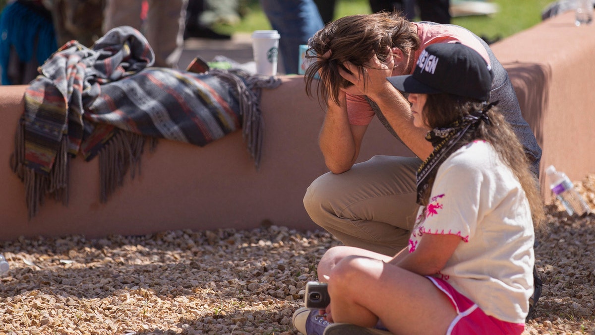 A protester places their head in their hands after a shooting in New Mexico