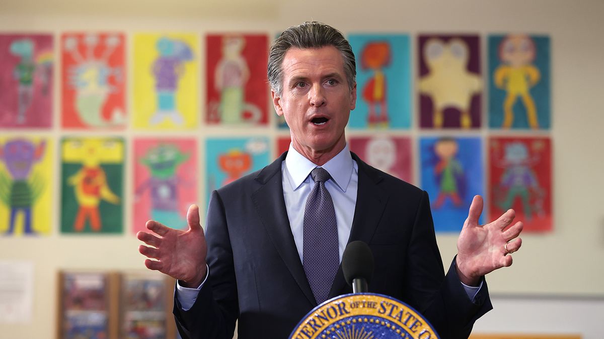 Gavin Newsom speaking at lectern in middle school