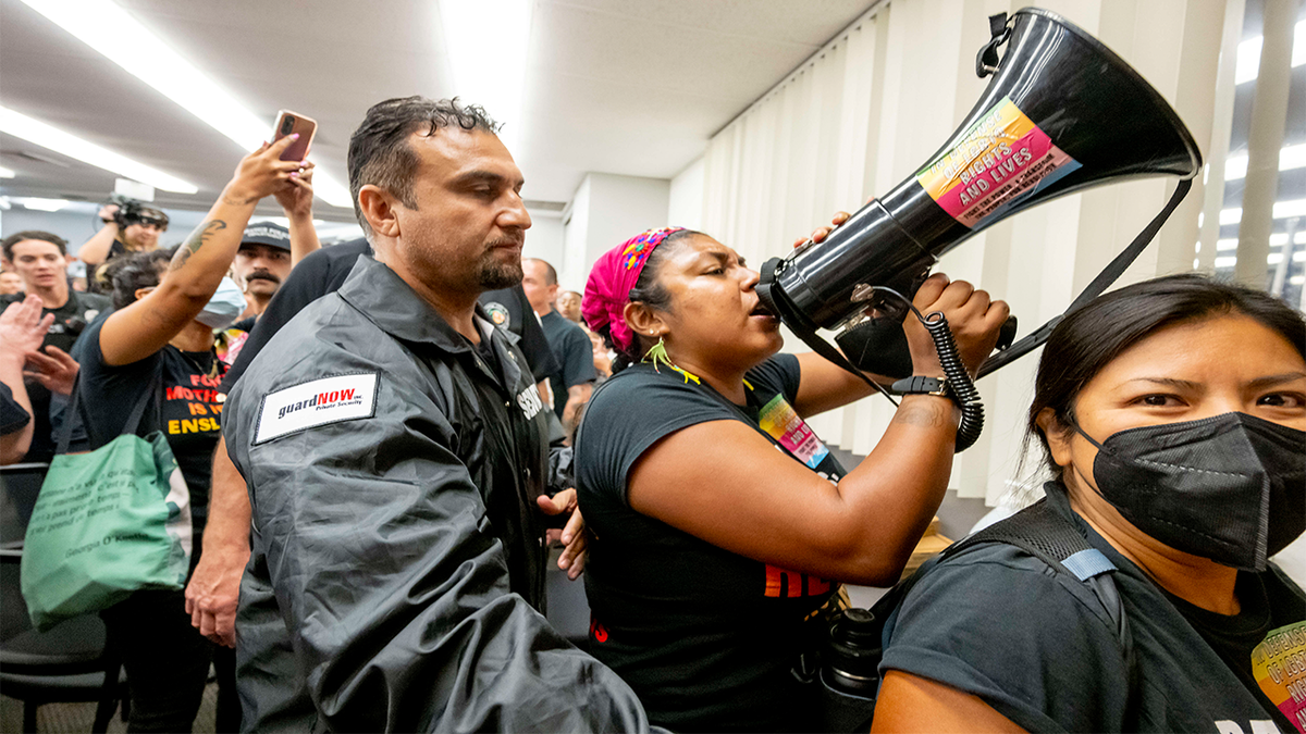 photo of protesters being escorted out of Orange unified school board meeting