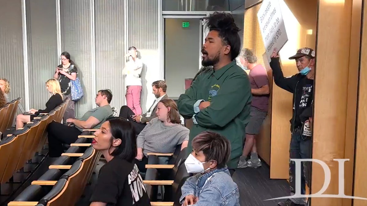 Activists hold signs and shout in Seattle city hall