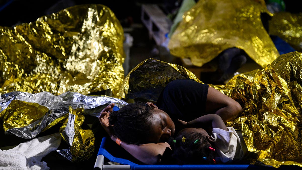 A woman and a child sleep outside Lampedusa's migrant reception center on Sep. 14, 2023. 