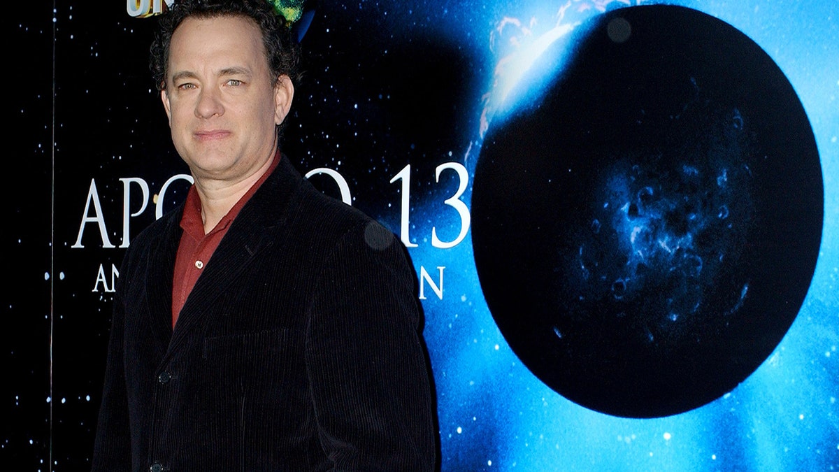 Tom Hanks standing in front of a picture of the moon