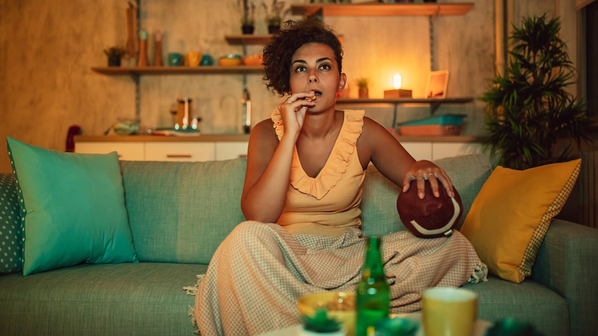 Woman with beer watching American football match on TV