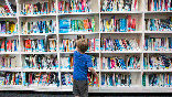 boy in library looking at bookshelf