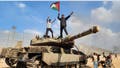 GAZA CITY, GAZA - OCTOBER 07: Hamas' armed wing, the Izz ad-Din al-Qassam Brigades hold a Palestinian flag as they destroy a tank of Israeli forces in Gaza City, Gaza on October 07, 2023. (Photo by Hani Alshaer/Anadolu Agency via Getty Images)