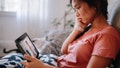 Young woman using a digital tablet to have a telemedicine video meeting with her doctor about the virus symptoms.