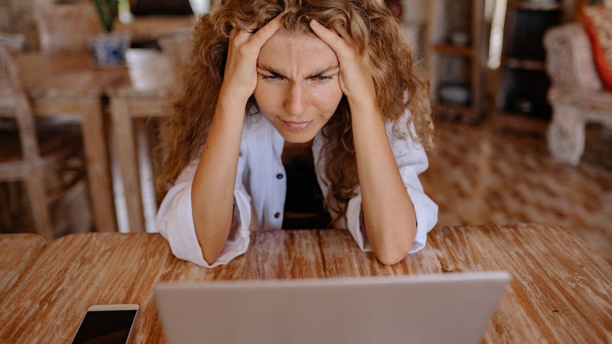 Visibly upset woman staring at her laptop.