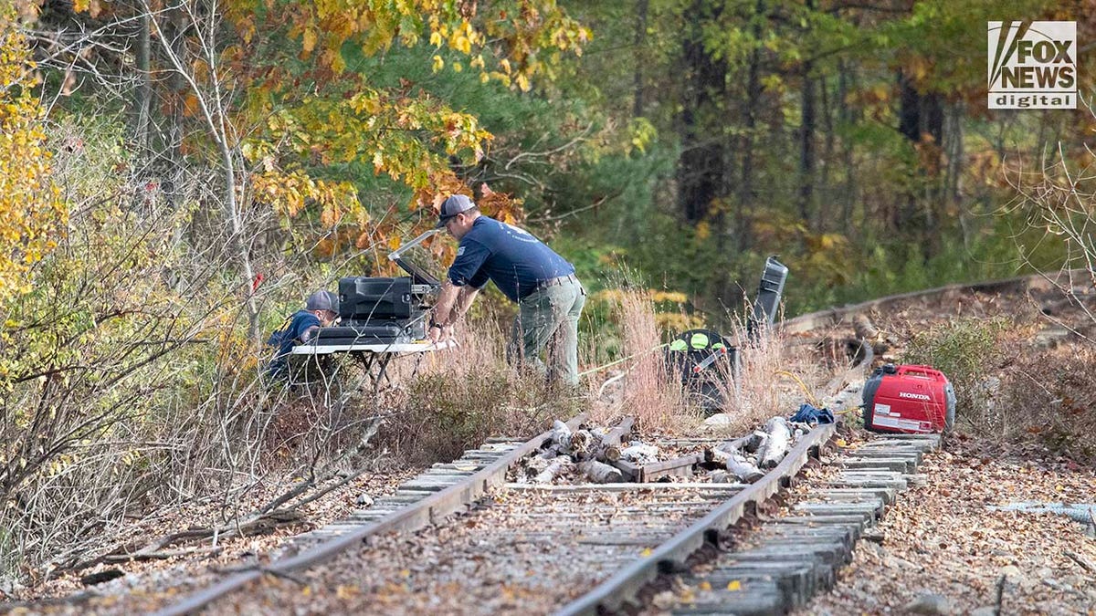 Law enforcement agents aid in the search for Robert Card along nearby railroad tracks by the Androscoggin River