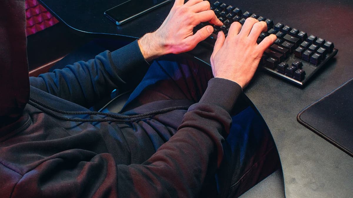 man sits at desk with hands on keyboard