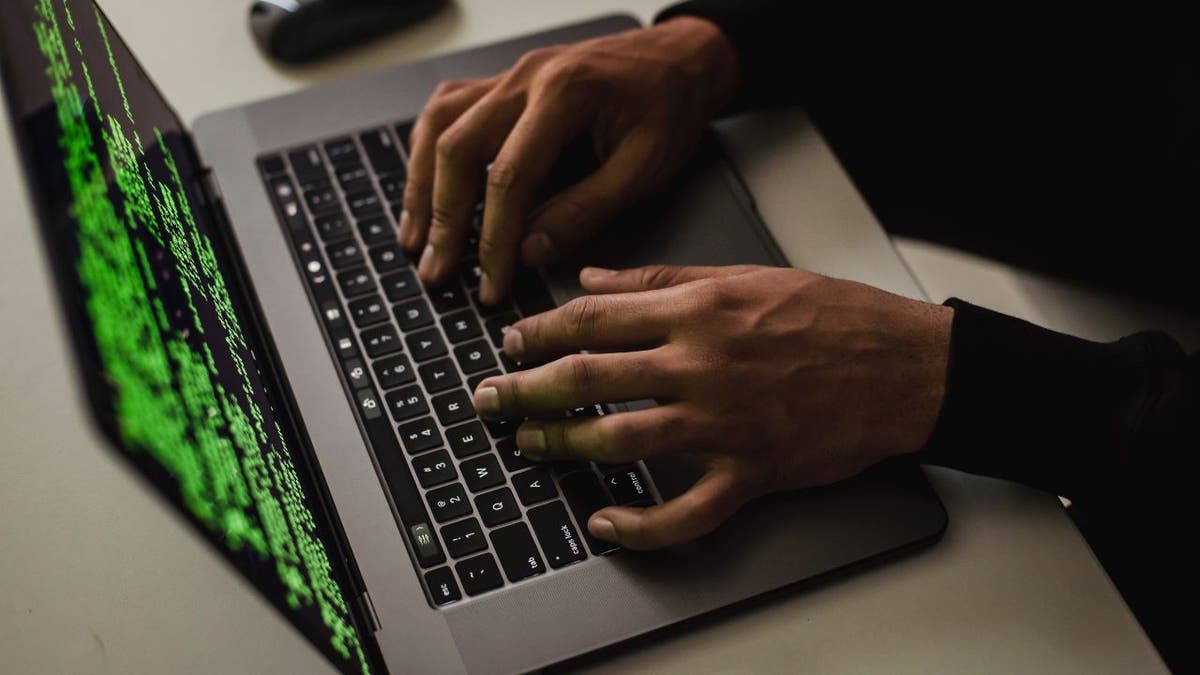 Photo of hacker on laptop.