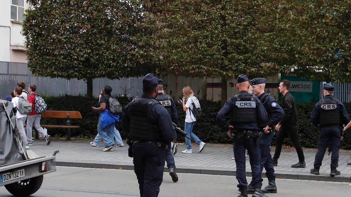 Heavily armed police stand guard as children are escorted to safety