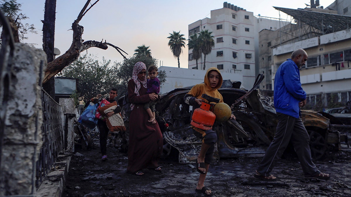 Palestinians carry belongings as they leave al-Ahli hospital