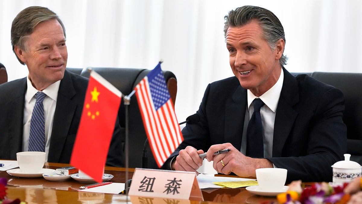 Newsom with American and Chinese flags on the table