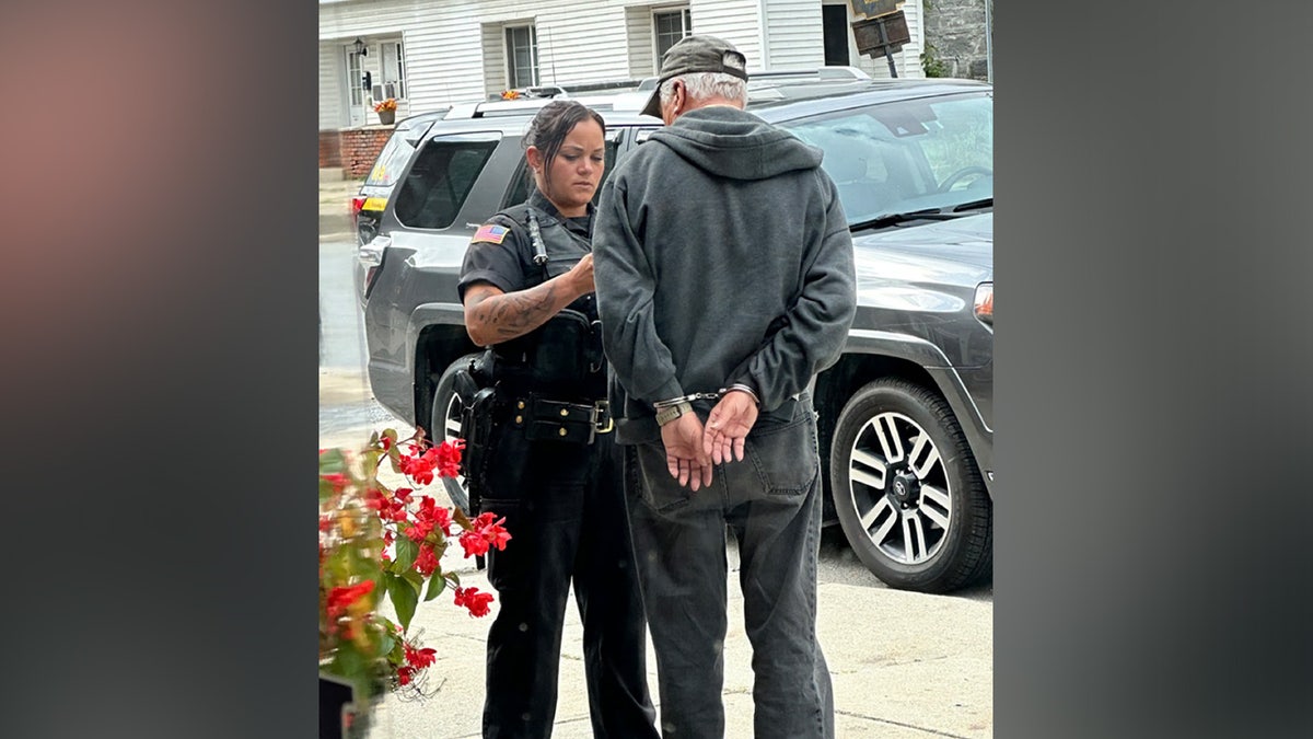 Deputy putting elderly man in handcuffs.