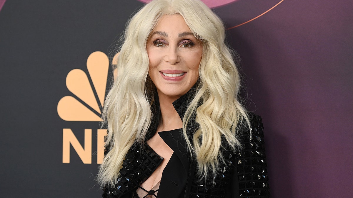 Cher with blonde hair smiling on the red carpet