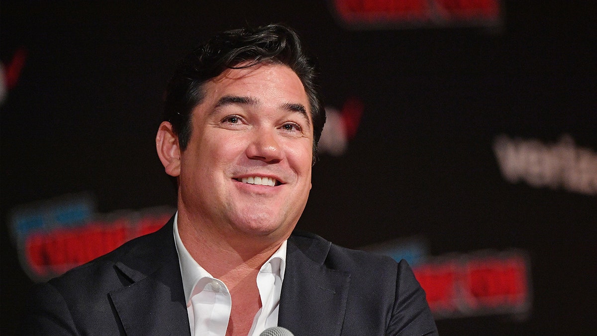 Dean Cain holding microphone on stage