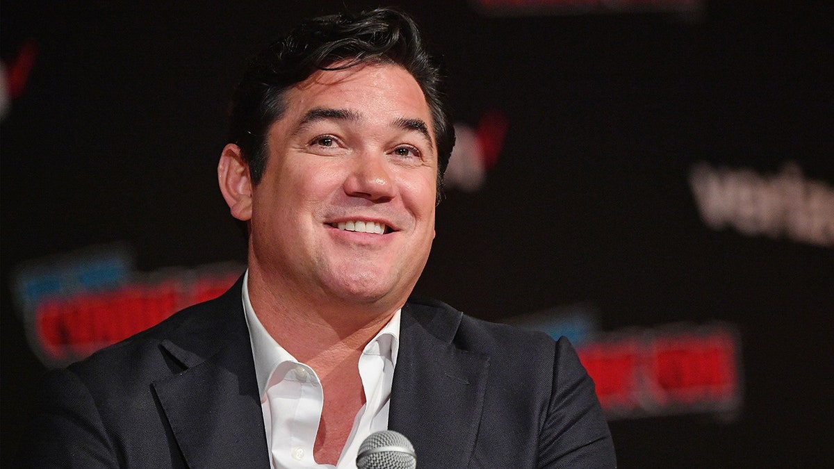 Dean Cain holding microphone on stage