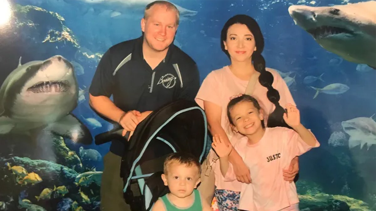 A family of four stand in front of a shark mural.