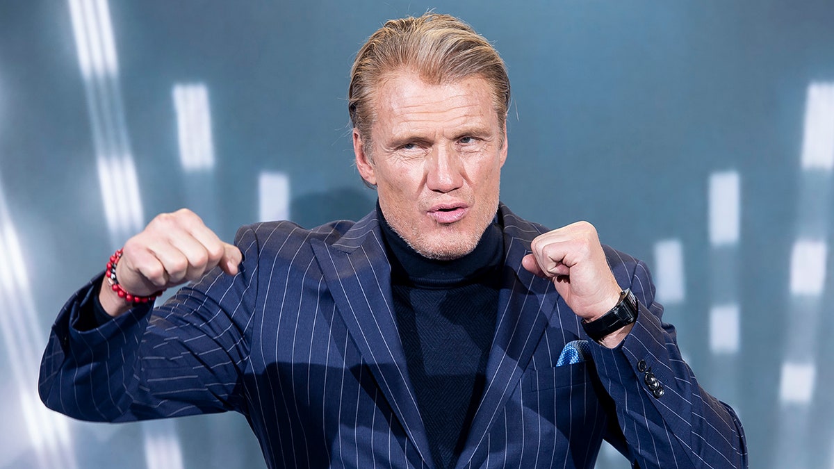 Dolph Lundgren posing like he's throwing a punch on the red carpet