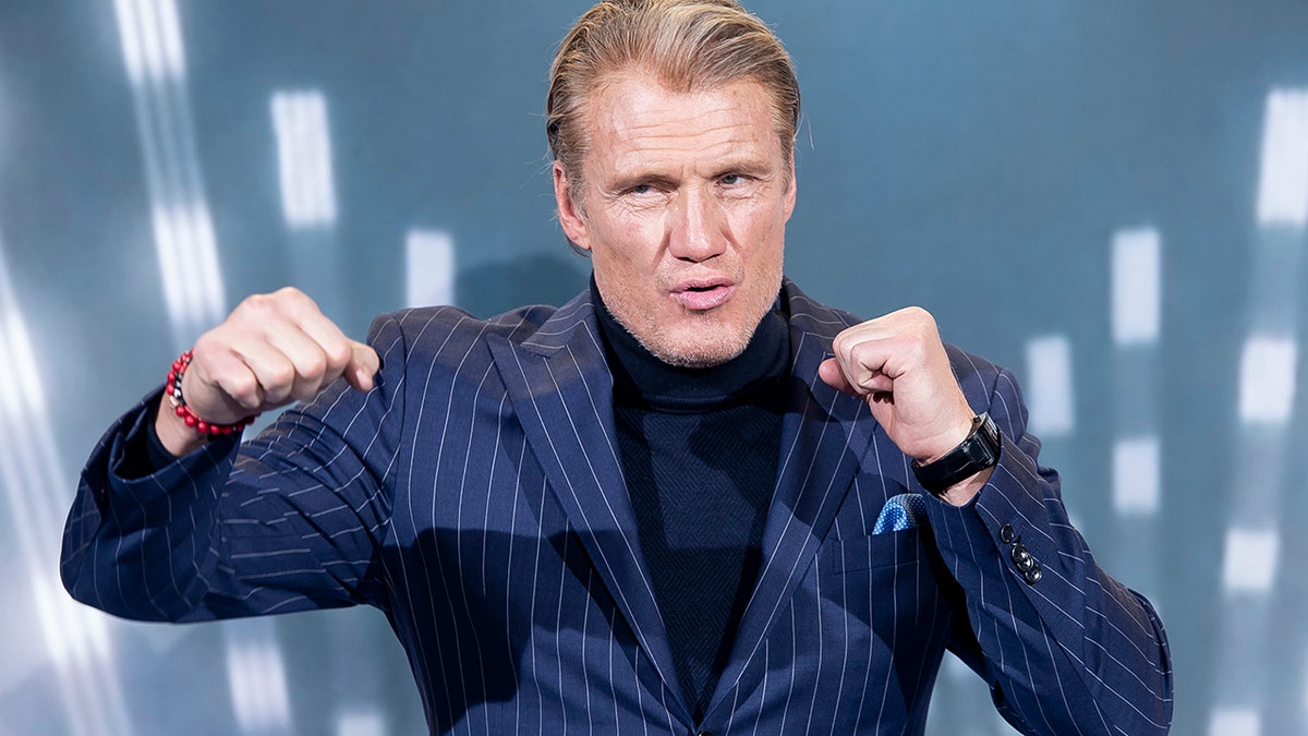 Dolph Lundgren posing like he's throwing a punch on the red carpet