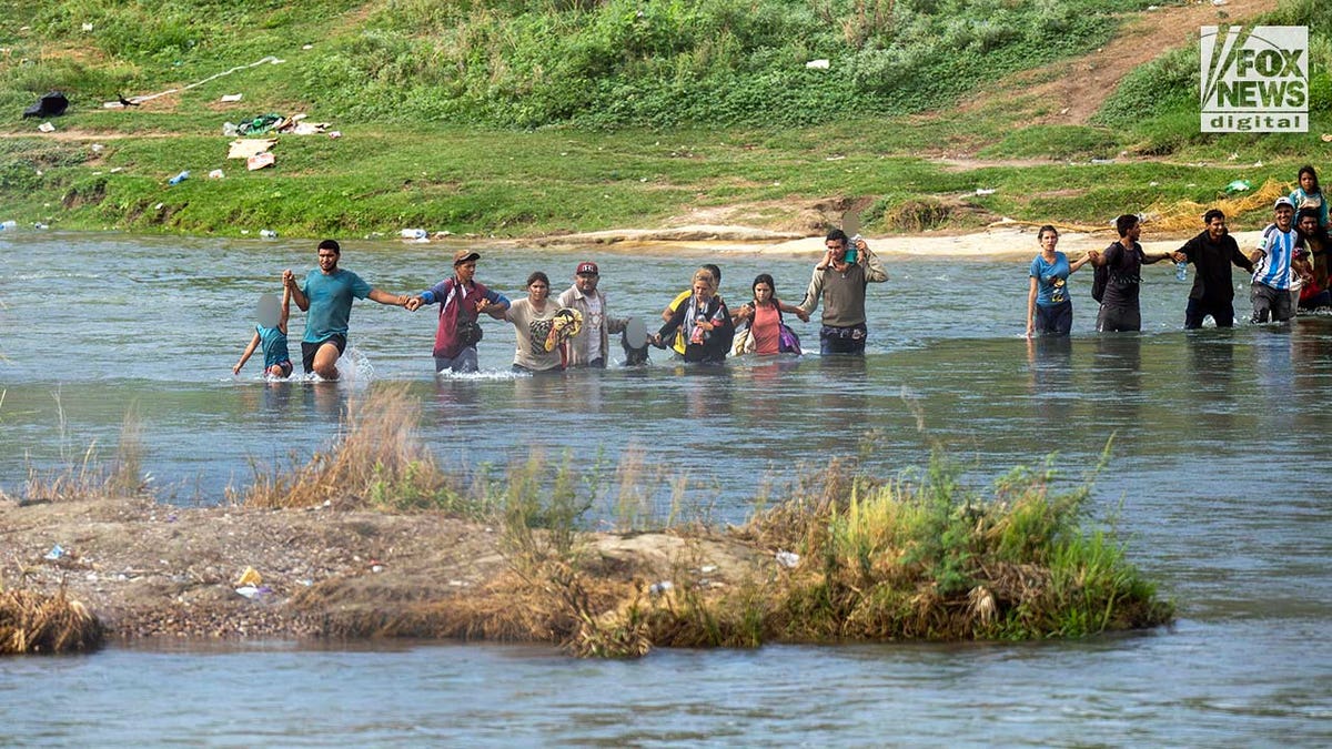 A group of migrants, some carrying children, cross the Rio Grande River in Eagle Pass, Texas on September 27, 2023. Border crossings through Eagle Pass continues to strain law enforcement as an unprecedented number of migrants enter the United States each day.