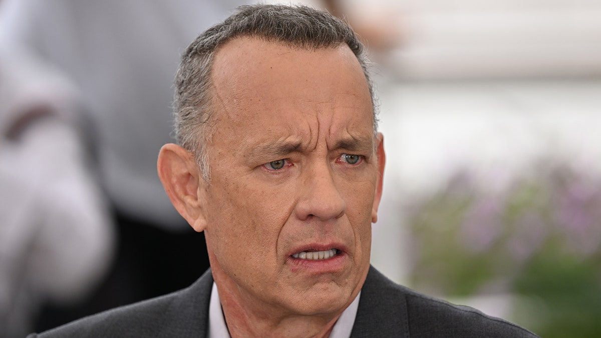 Tom Hanks looks confused as he looks away from the camera at something