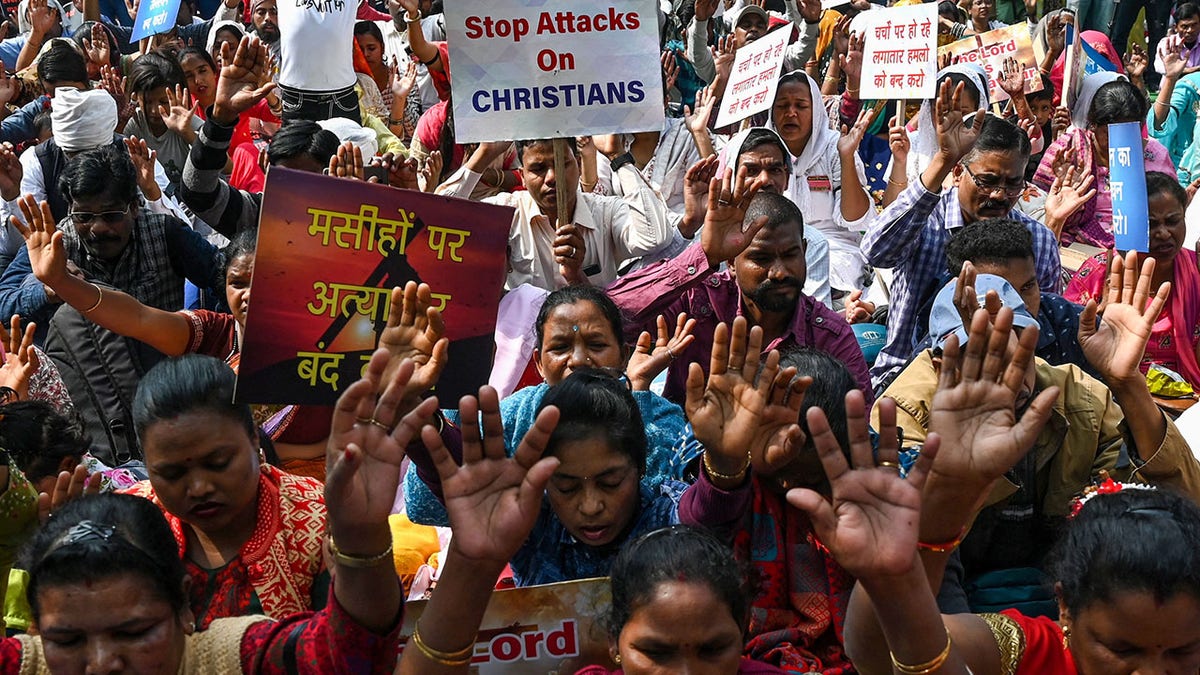 Crowd protests; sign says "stop attacks on CHRISTIANS"