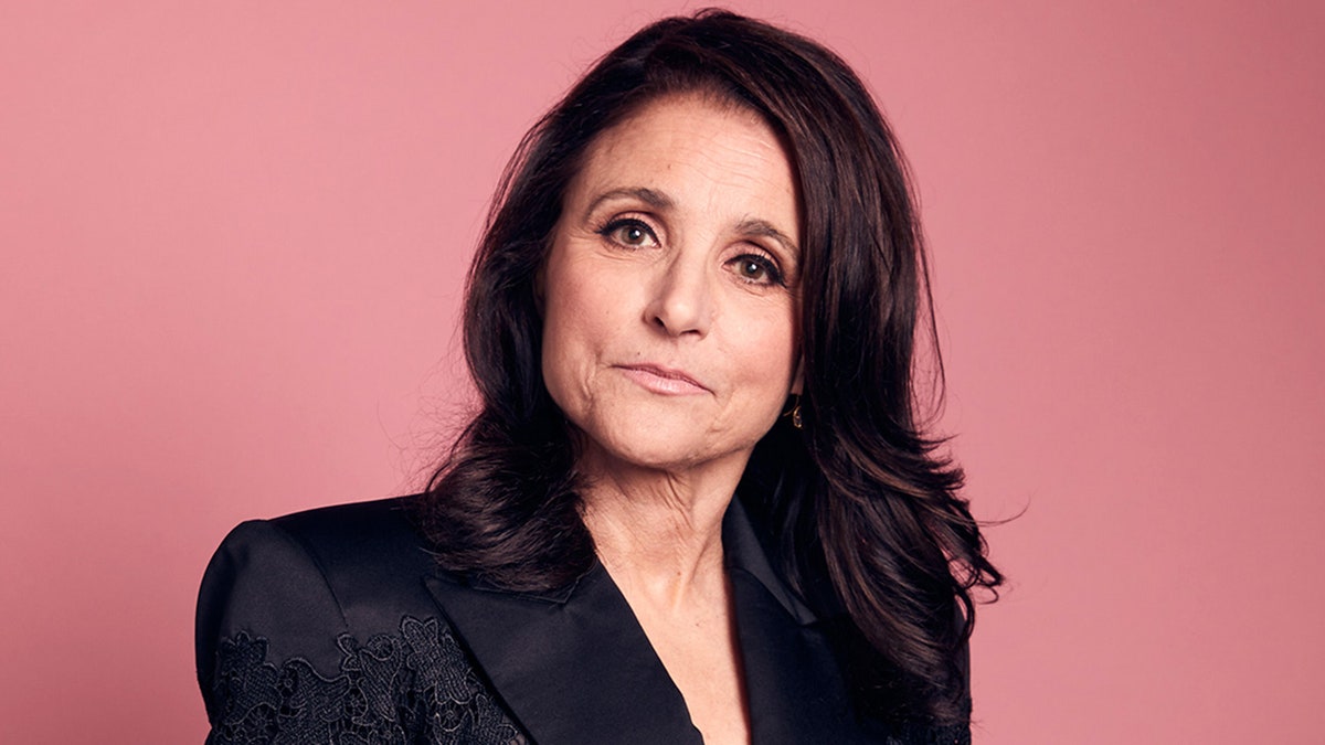 Julia Louis Dreyfus tilts her head slightly and looks directly at the camera, not smiling