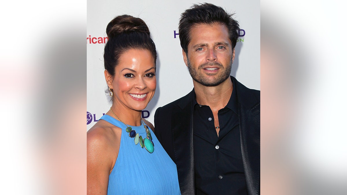 Brooke Burke in a blue dress and bun hairdo with husband David Charvet in black