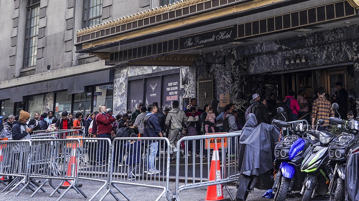 Migrants lined up on sidewalk in Manhattan outside historic Roosevelt Hotel