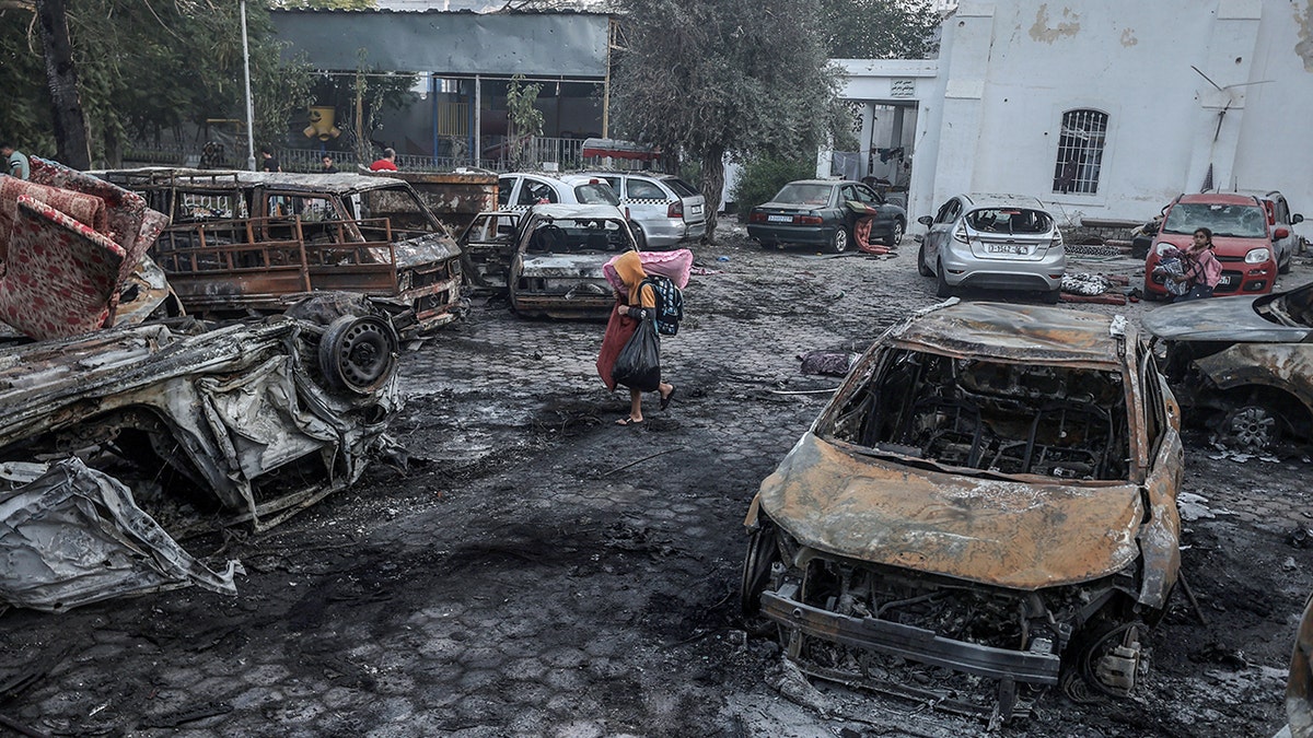 A boy tries to collect usable belongings amid wreckage of vehicles after Al-Ahli Baptist Hospital was hit in Gaza City, Gaza on October 18, 2023.