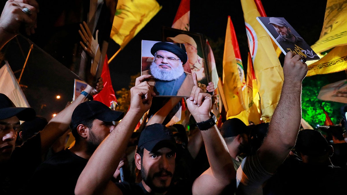Protesters hold up photos of Hezbollah chief outside US embassy Baghdad