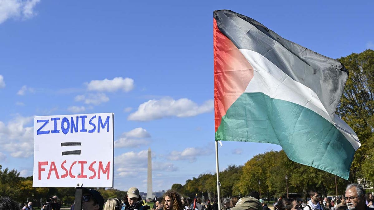 Demonstrators with sign "zionism = fascism" and palestinian flag