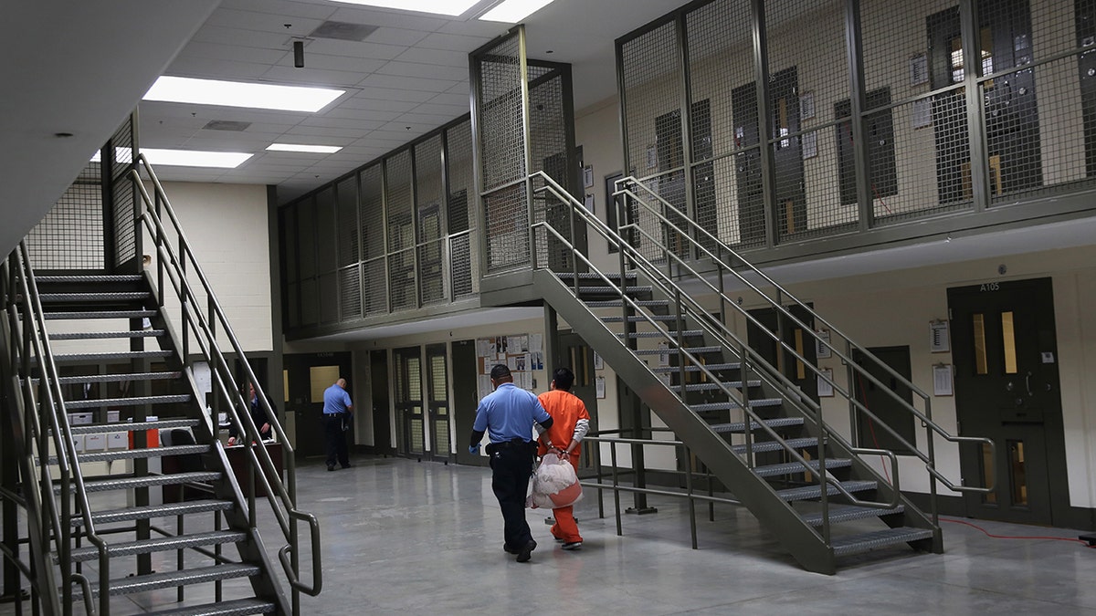 A guard escorts an immigrant detainee from his segregation cell back into the general population at the Adelanto Detention Facility on November 15, 2013, in Adelanto, California.