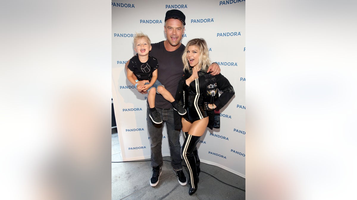 Josh Duhamel holding son Axl while posing with Fergie