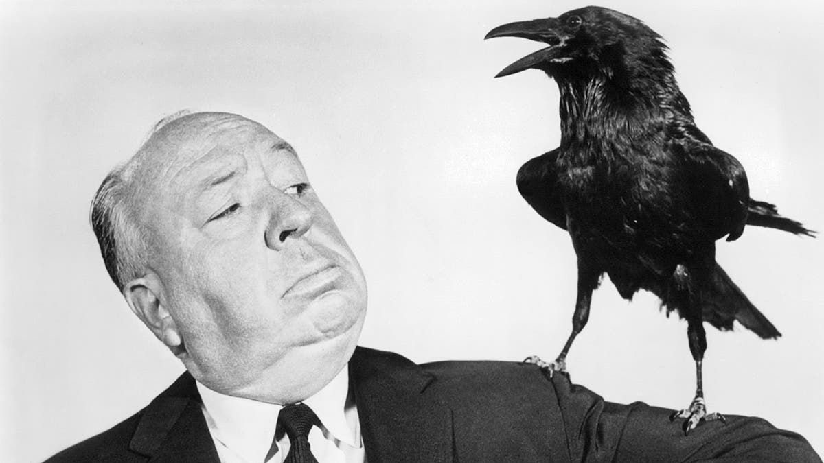 Alfred Hitchcock posing with a stuffed crow